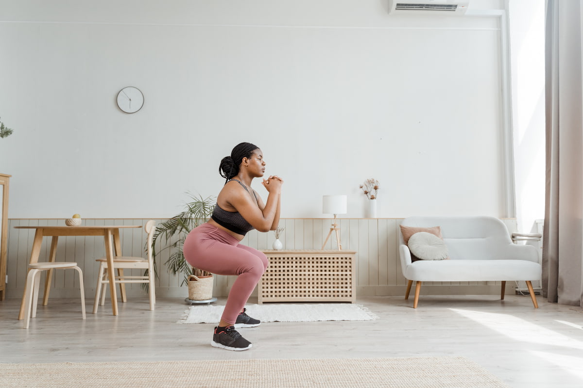 Woman doing bodyweight squats during a workout from home