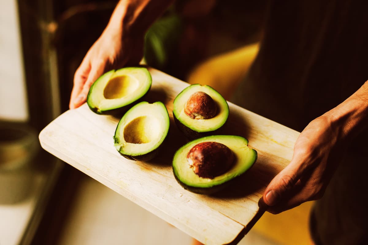 Man holding avocados cut in half
